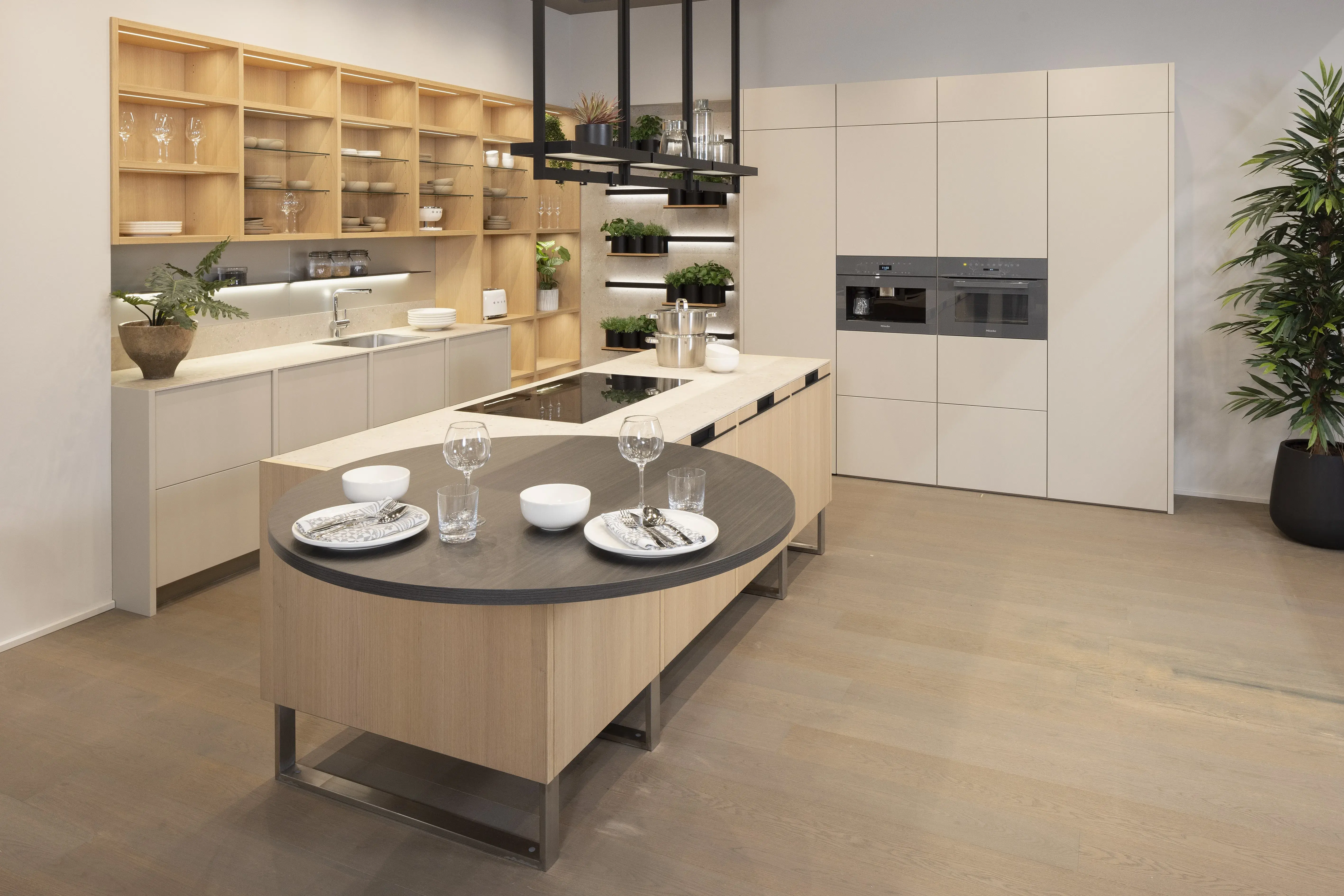 Moderne Küche mit Kochinsel, gedecktem Tisch, hellen Schränken und viel Tageslicht.